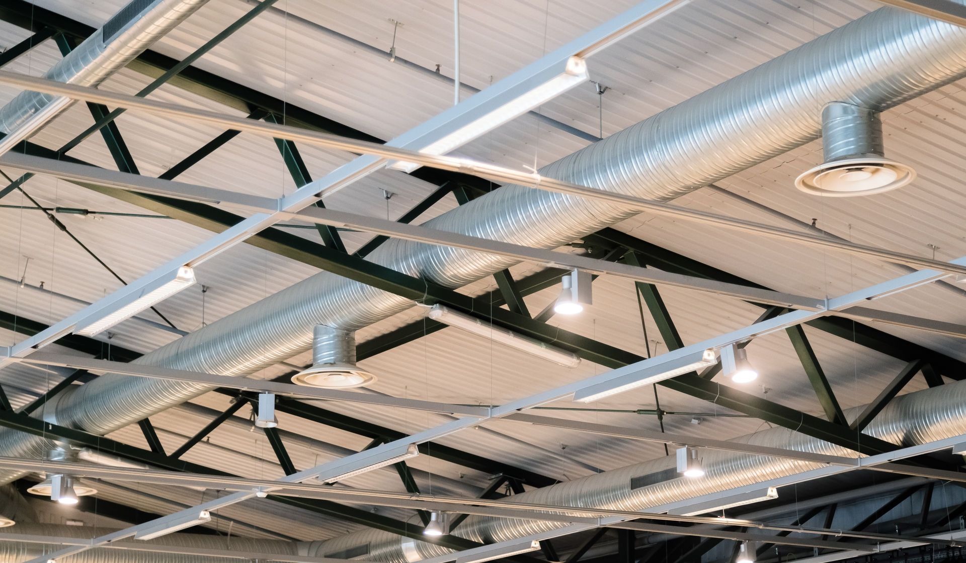 Industrial facility with high-bay LED lighting illuminating heavy equipment and steel structural framework