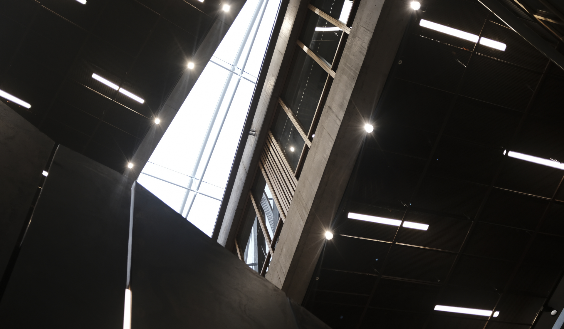 Large warehouse interior with rows of LED panel lights illuminating stacked pallets and distribution aisles